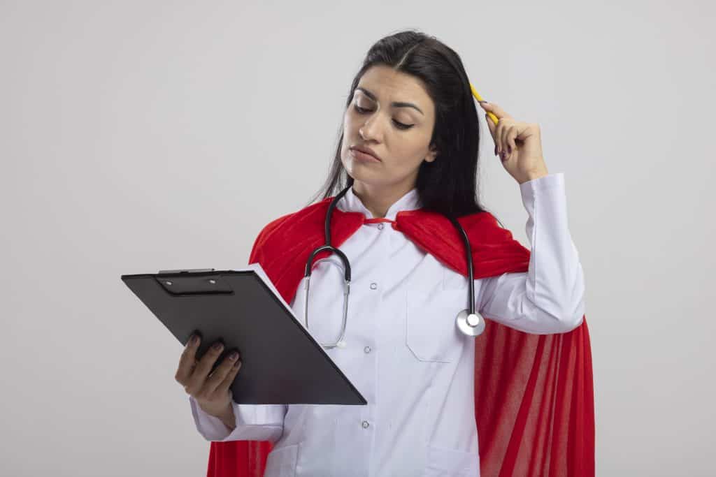 Female doctor with a red cape reading a clipboard, thinking deeply.