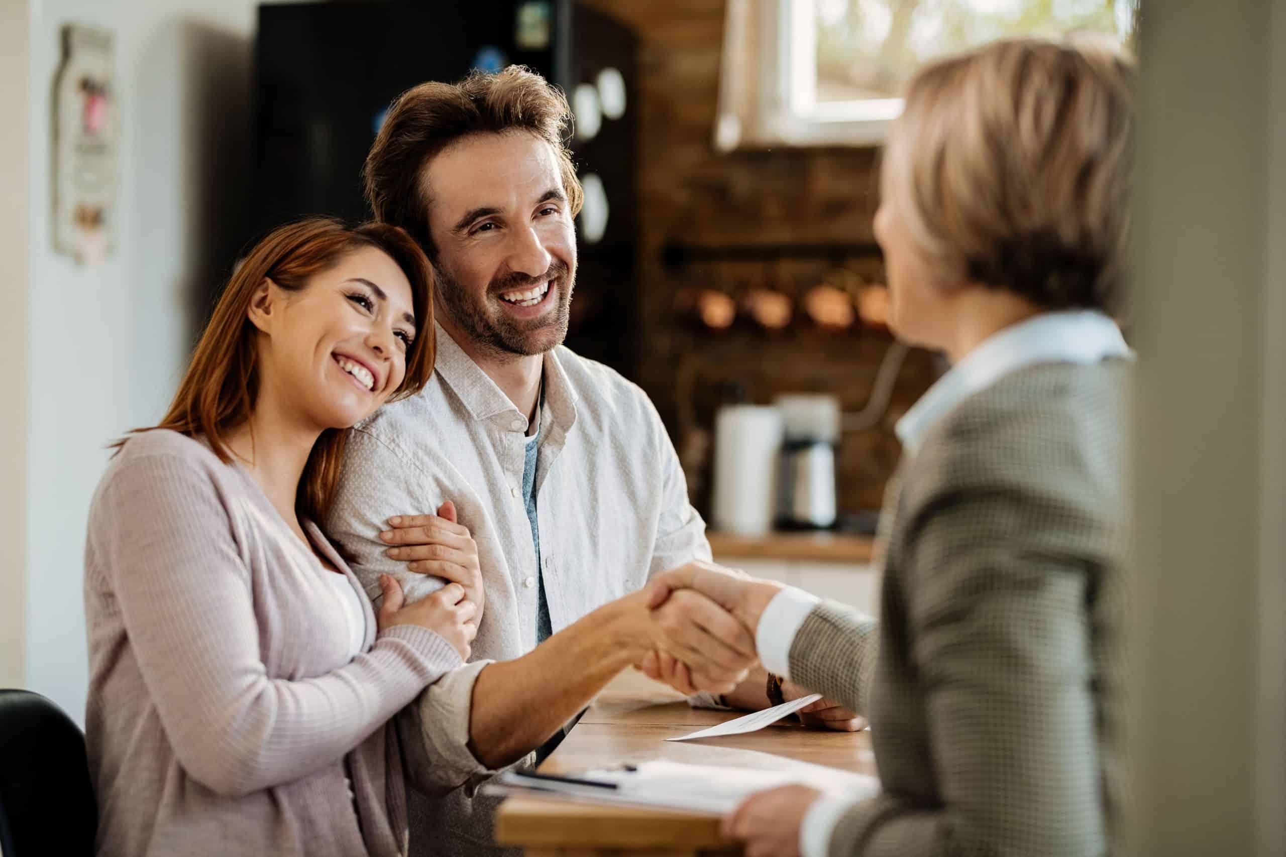 Happy couple consulting with insurance broker in cozy office setting.